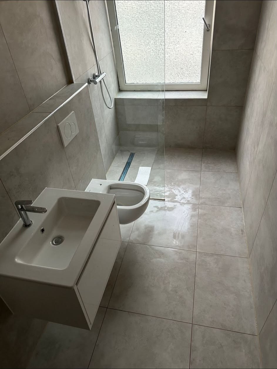 Bad nach der Sanierung: großformatige Fliesen, bodengleiche Dusche, Wand-WC und Waschtisch