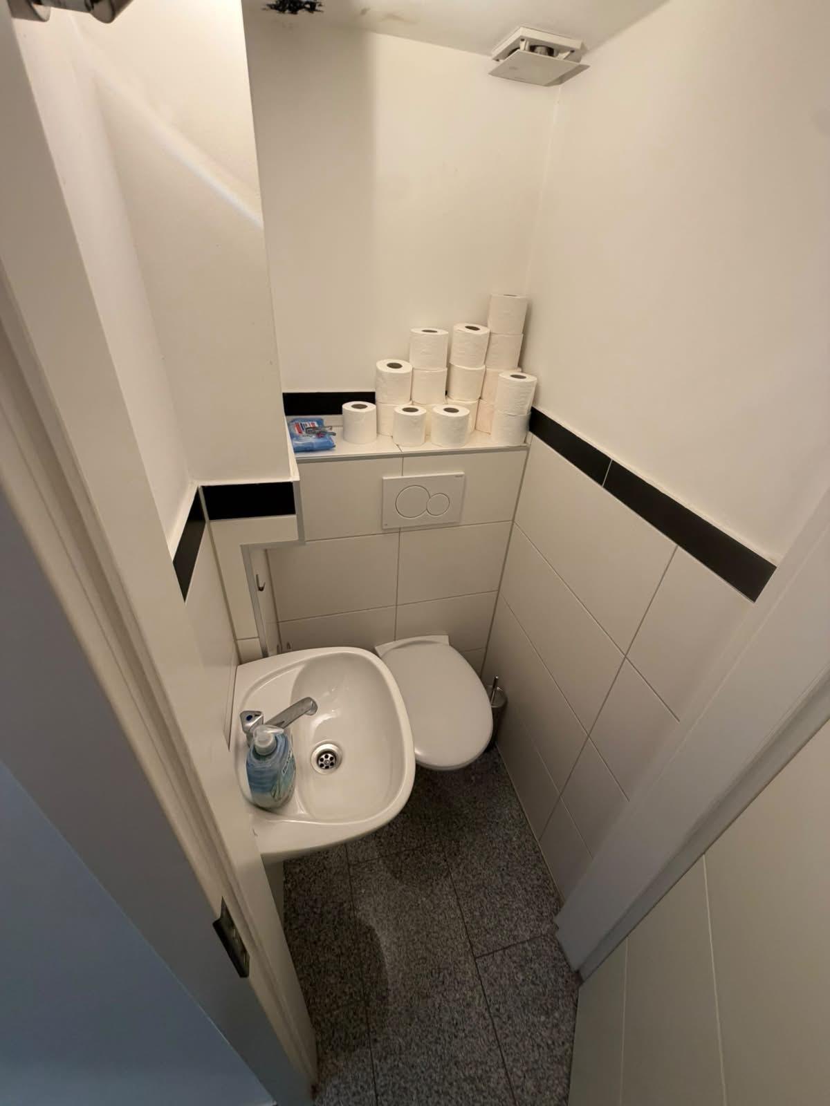 Gereinigtes Gäste-WC in einem Büro mit Handwaschbecken und Vorrat an Toilettenpapier, Düsseldorf-Oberbilk