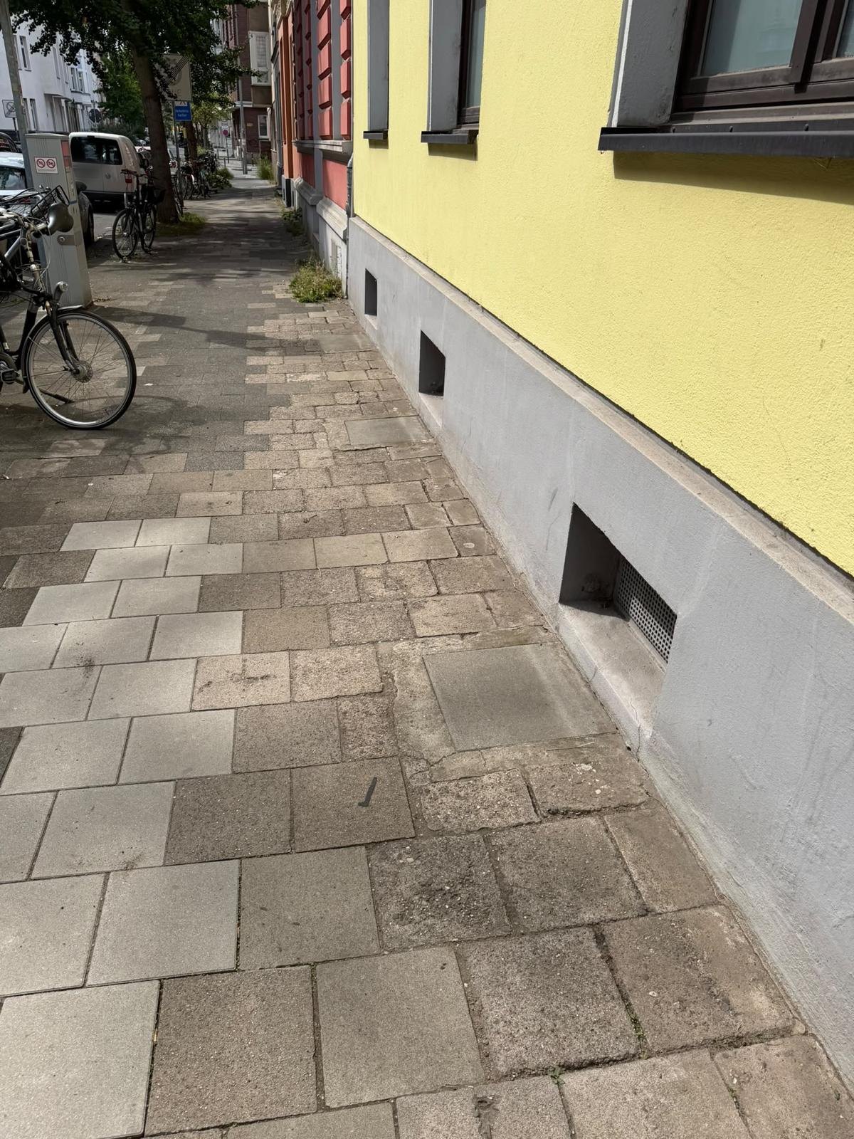 Gepflegter Gehweg entlang einer gelben Hausfassade ohne Unkraut in den Fugen, Düsseldorf-Unterbilk