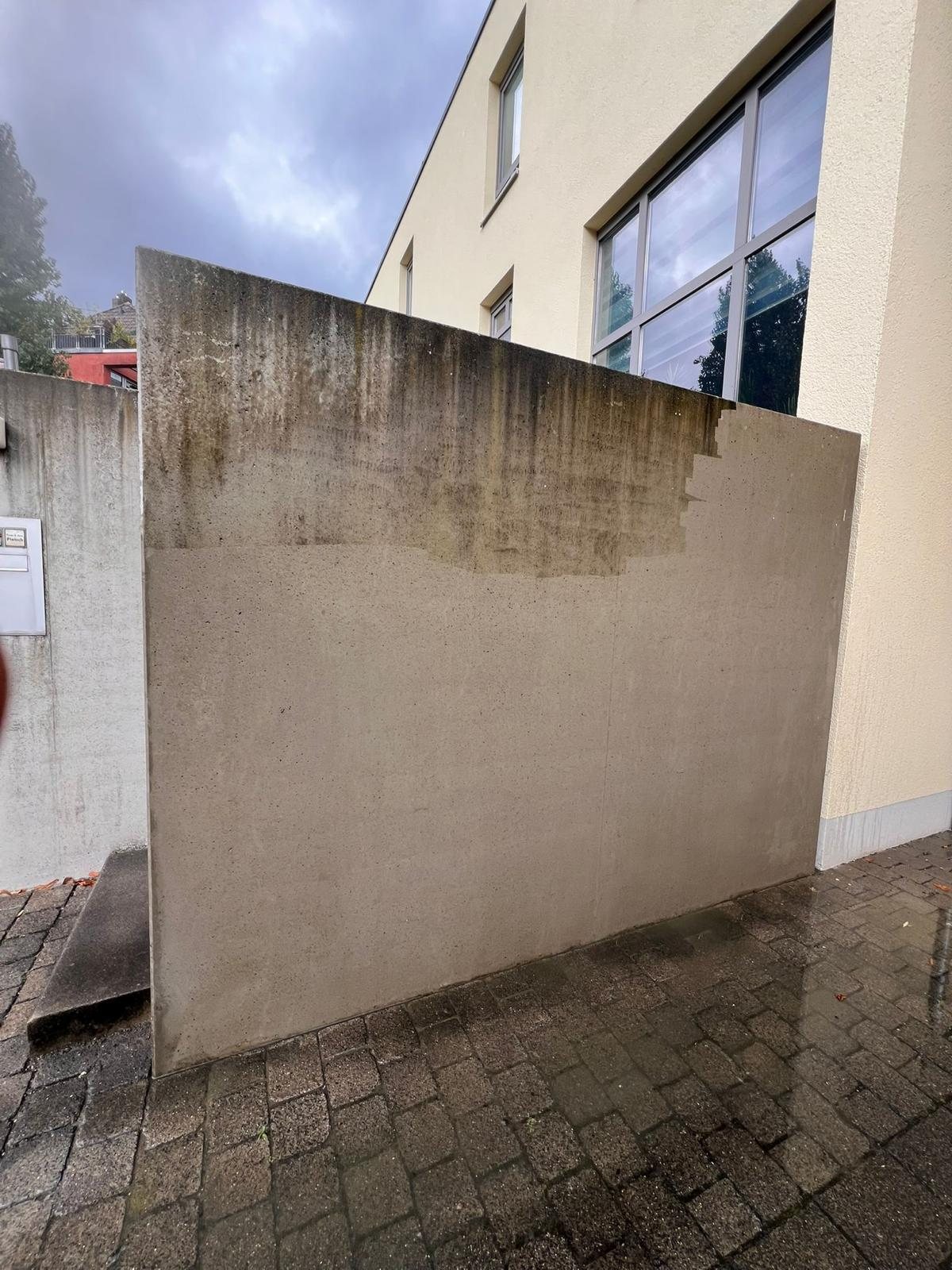 Betonwand während der Hochdruckreinigung, obere Hälfte noch verschmutzt, untere Hälfte gereinigt, Düsseldorf-Oberbilk